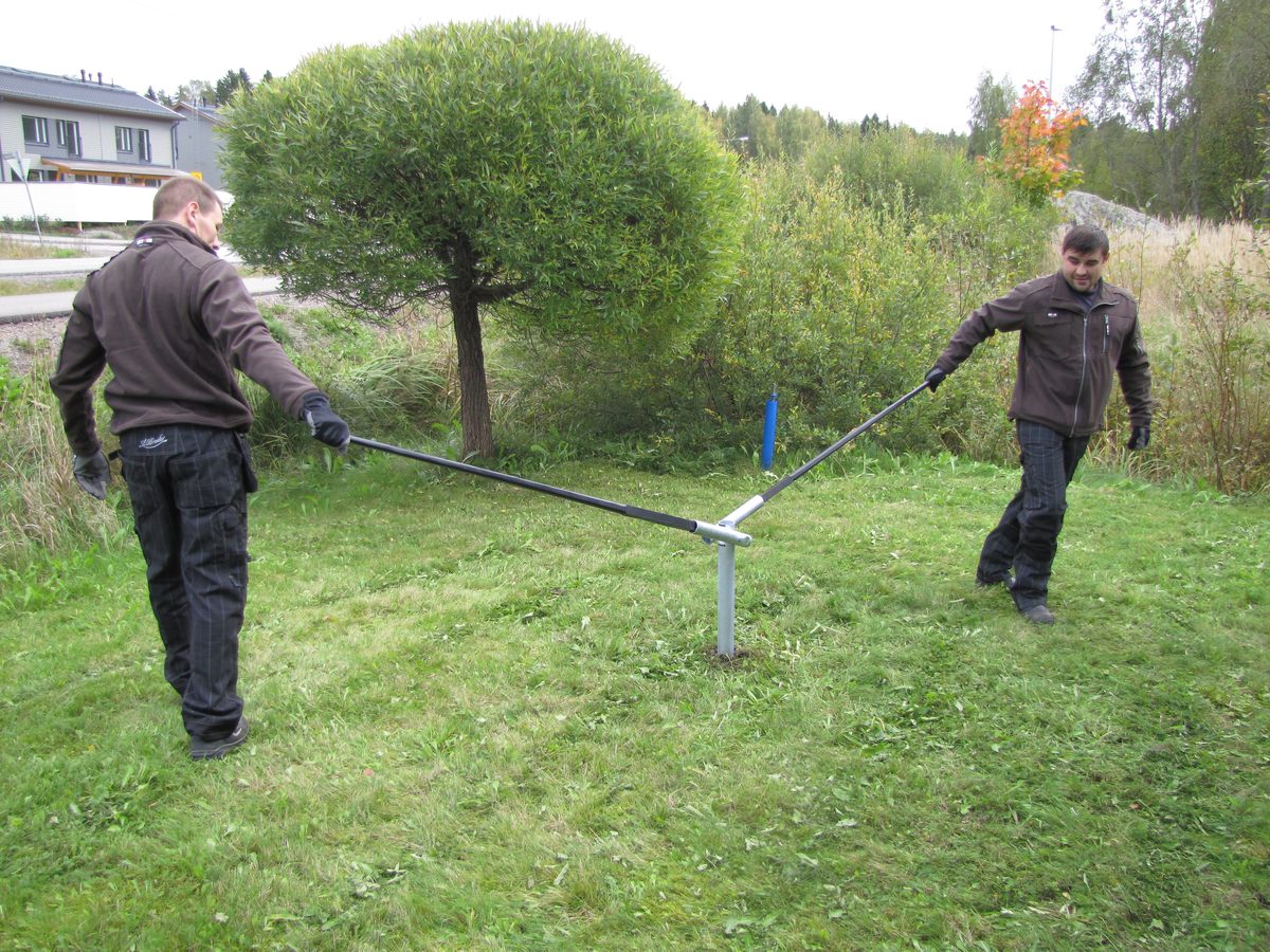 Two people installing a HELIX screw pile with the SR100 installation kit